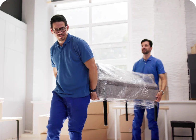 Two men carrying a wrapped couch.