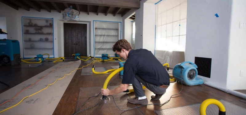 Person setting up equipment for water damage restoration.