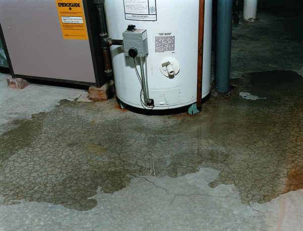 Leaking water heater with surrounding puddle.