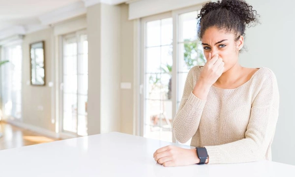 Person holding nose, sitting at white table.