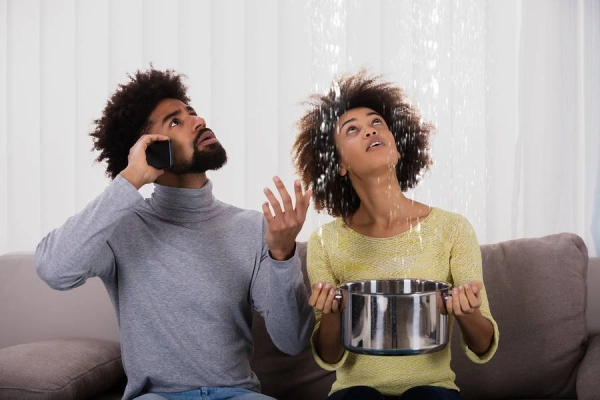 Couple dealing with ceiling water leak indoors.