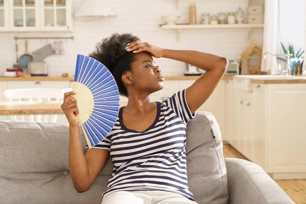 Woman fanning herself on living room couch.
