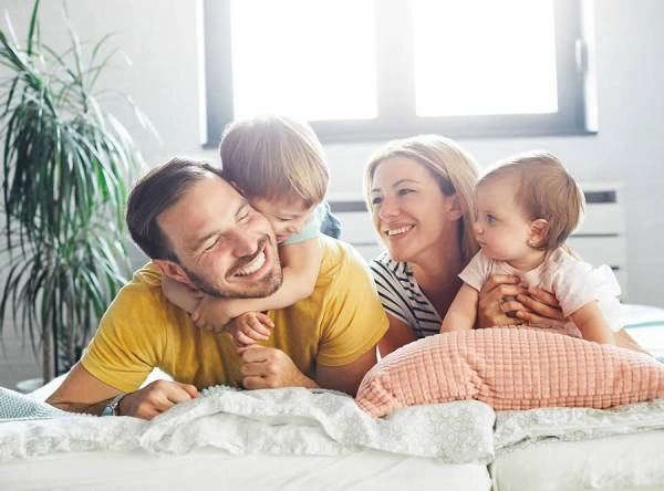 Happy family playing on a bed together.