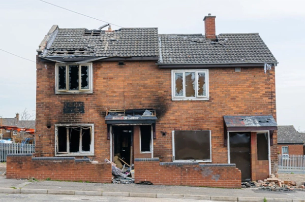 Burnt-out brick house with broken windows.
