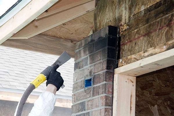 Person cleaning soot from brick chimney exterior.