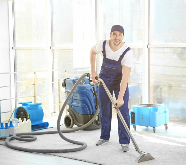 Man cleaning carpet with vacuum equipment.