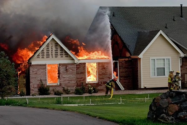 House engulfed in flames with firefighters responding.