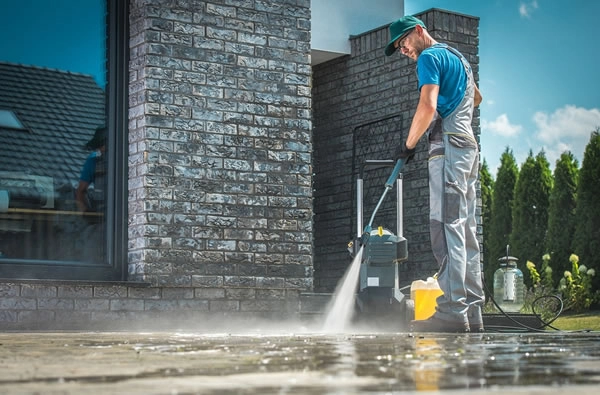 Man pressure washing a patio surface.
