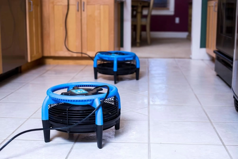 Floor fans drying tiled kitchen floor.