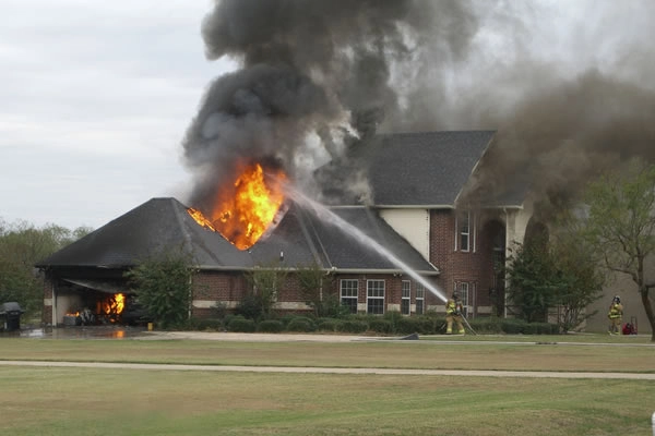 House on fire with firefighters responding.